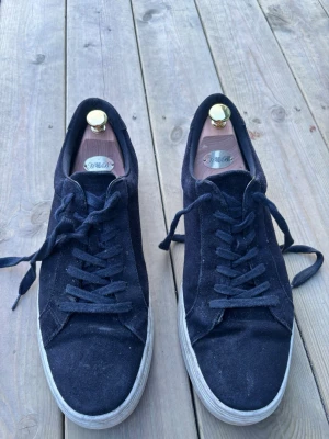 Svarta mockasneakers med vit sula - Stilrena svarta sneakers i mocka med klassisk vit sula och svarta skosnören. De är i bra skick 