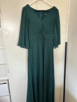 Lång mörkgrön festklänning - Mörk grön lång fest klänning. Knappt använd så den är fortfarande i väldigt fint skick. Passar jätte fint på kroppen, stl S men passar lika bra för stl M. Köpt för 500kr OBS!! Det finns lösa sömmar då den är lång, men de syns inte när klänningen är på. Den är också insydd vid bröstet, det kan tas ut ifall man vill.