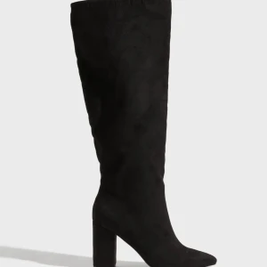 Boots Nelly - Säljer ett par svarta knähöga boots i mockaimitation med spetsig tå och bred klack från Nelly. Stövlarna har en stilren och trendig look som passar perfekt till kjol eller klänning. Skriv för fler bilder m.m.
