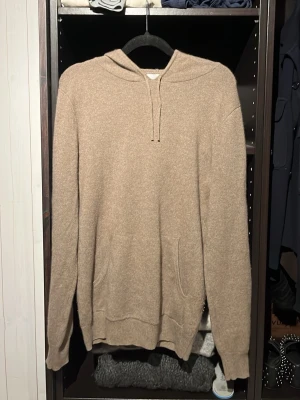 John Henric kaschmir hoodie  - Mjuk och lyxig beige hoodie från John Henric i 100% cashmere. Klassisk modell med huva, dragsko och känguruficka framtill. Perfekt för dig som vill ha en stilren och bekväm look med exklusiv känsla. Passar till jeans eller mjukisbyxor. Inga defekter som ny säljer för att den inte kommer till användning pris kan diskuteras