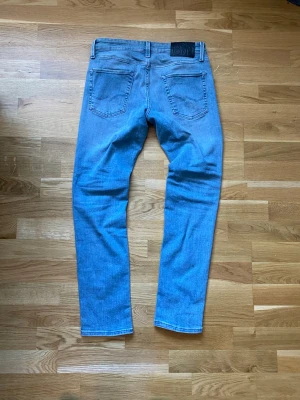  slim fit Jack & Jones  - Säljer ett par ljusblå slim fit jeans från Jack and Jones med klassisk femficksmodell och skinnpatch bak i midjan. Kan gå ner i pris vid snabb affär.