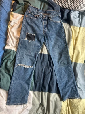 Levis - Ett supersnyggt par jeans från Levis. Snygga lagningar och slitningar vid fotändan(går att klippa bort trådarna om man vill). W32 L32. Rak passform. Skriv om du har frågor eller vill diskutera priset!