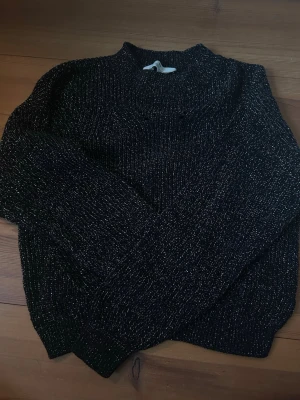 Glittrig stickad tröja - Jättefin svart stickad tröja med glittrig tråd instickat i materialet. Jättemysig och festlig! Strl 158/164. Skriv om du har frågor!