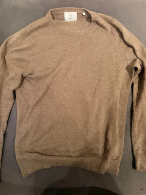 Beige stickad tröja från Bläck - Säljer en stilren beige stickad tröja från Bläck. Tröjan har rund halsringning, ribbade muddar vid ärmslut och nederkant samt en mjuk och tunn stickning som passar perfekt till lager på lager. Enkel och snygg design som funkar till det mesta.