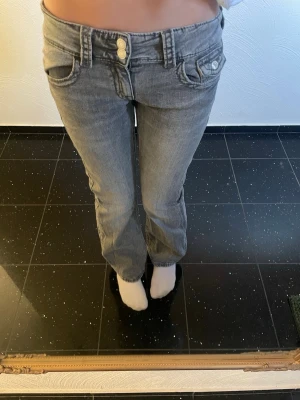 Gråa low waist jeans med dubbla knappar - Säljer ett par gråa low waist jeans med raka ben och dubbla knappar i midjan. De är i storlek 158💞