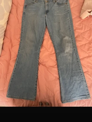 Blå lågmidjade bootcut jeans i klassisk modell från Levis - Ett par ljusblå bootcut jeans med hög midja och klassisk femficksdesign. Jeansen har utsvängda ben och är tillverkade i ett mjukt denimtyg. Perfekta för dig som gillar retrostil och vill ha ett par bekväma jeans med snygg passform.