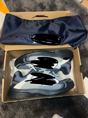 Svarta och vita chunky sneakers - Snygga chunky sneakers i svart, vitt och grått med mesh- och läderdetaljer. Skorna har vita snören och en rejäl sula som ger en sportig vibe. Perfekta för dig som gillar streetwear och vill ha något som sticker ut.