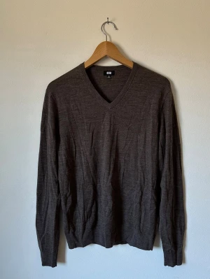 Mörkbrun V-ringad tröja Uniqlo - Säljer en mörkbrun stickad tröja från Uniqlo med V-ringning. Tröjan har långa ärmar och ribbade muddar vid ärmslut och nederkant. Tillverkad i tunt, mjukt material som passar perfekt för lager på lager. 6R11
