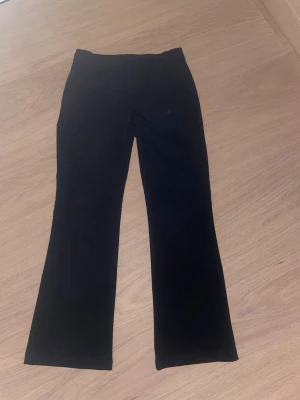 Svarta bootcut kostymbyxor från Lindex  - Säljer ett par svarta kostymbyxor med bootcut-modell i storlek 146. Byxorna har fickor fram och bälteshällor, vilket gör dem både snygga och praktiska. Materialet är mjukt som ger en skön känsla.skriv för fler bilder,pris kan diskuteras!💗