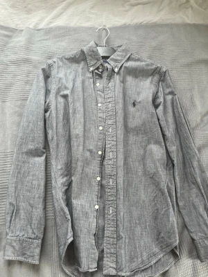 Grå skjorta från Ralph Lauren - Snygg grå skjorta från Ralph Lauren i slim fit-modell. Skjortan har storlek m slim-fit. Har växt ur mig och säljer av den anledningen. Skicket är mycket bra. Vad jag kan se inga större tecken på användning. Skriv vid intresse. Pris kan diskuteras