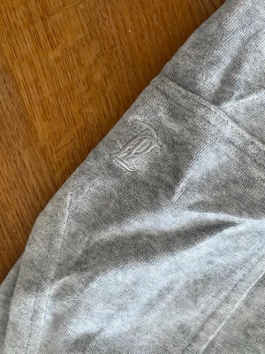 Grå mjuka juicy couture byxor - Gråa juicy couture i mjukt och stretchigt material med raka ben och bred resår i midjan. Byxorna har två bakfickor och en diskret broderad logga framtill. Perfekta för chill dagar hemma.