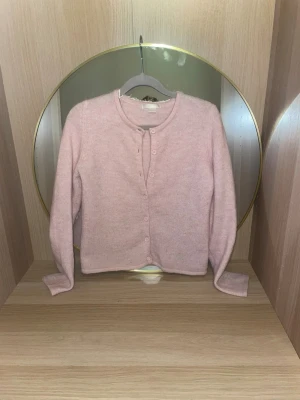 Ljusrosa kofta från Gina Tricot - Söt ljusrosa kofta från Gina Tricot med rund halsringning och knappar framtill i storlek 146-152.Koftan är stickad i ett mjukt material och har långa ärmar. Perfekt att slänga över en topp för en chill look.skriv för fler bilder,pris kan diskuteras!💗(skulle säga att den sitter som en xs),