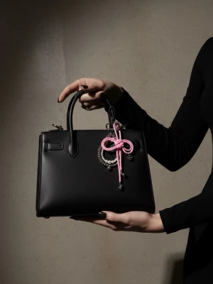 Handgjord Söt Nyckelring & Väskcharm – Rosa Rosett med Pärlor - Superfint och unikt handgjort hänge som passar perfekt som nyckelring eller väskcharm. Den har en söt ljusrosa rosett knuten av paracord-snöre och är dekorerad med eleganta vita pärlor, metallkulor och ett litet blommigt hänge. 