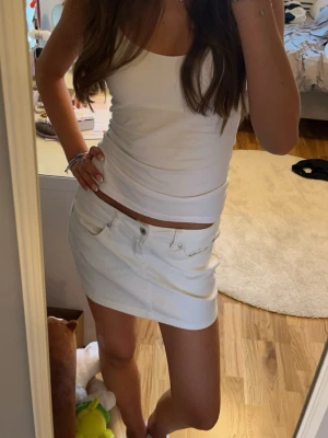 Vit jeanskjol - Snygg vit minikjol i jeansmaterial med klassiska fem fickor och knappgylf. Kjolen har en tight passform och är perfekt till sommaren. Säljer då den blivit för liten💗