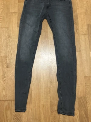 Mörkgrå slim fit jeans - Säljer ett par mörkgråa skum fit-jeans med klassisk femfickdesign och smal passform. Jeansen har en lätt tvättad look och är tillverkad i stretchiga denimtyg för extra komfort. Perfekta för dig som gillar en stilren och enkel look. Jeansen är använda några gånger och är i fint skick utan fläckar eller skador.                        Storlek: W32/L34                                                                                      