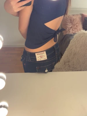 Mörkblå croppad topp med knyt - Snygg mörkblå croppad topp med öppen rygg och knyt i sidan. Toppen är ärmlös och har en enkel, stilren design som passar perfekt till jeans eller kjol. Materialet känns mjukt och lätt mot huden.