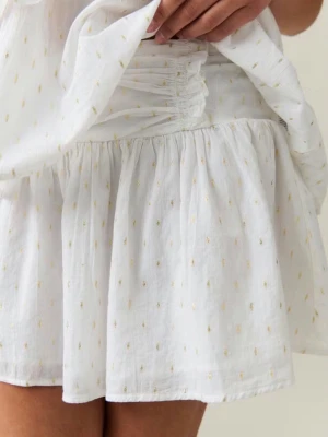 Vit kortkjol med smock och volang - Supersöt vit kortkjol med smock i midjan och volangkant. Kjolen har små diskreta broderade detaljer i gult och är gjord i ett lätt och luftigt bomullstyg. Perfekt för varma dagar och ger en fräsch och somrig vibe.💕