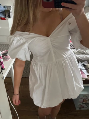 Vit off-shoulder klänning med puffärm - säljer min UNDERBARA sommaravslutningsklänning. perfekt för student eller sommaravslutning. den går att bära på två sätt som en offshoulder eller mer v-ringad version den har en öppenrygg med knytning och är bara använd en gång 🤍🤍 DEN ÄR SLUTSÅLD på hemsidan. kontakta för mer frågor! 