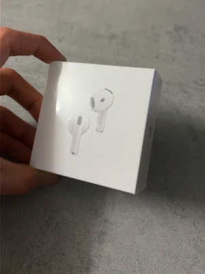 Apple AirPods trådlösa hörlurar - Säljer ett par vita Apple AirPods i originalförpackning. Trådlösa in-ear-hörlurar med stilren och minimalistisk design. Perfekta för musik, samtal och vardagsbruk. Kommer i en kompakt, vit kartong med Apple-logga.