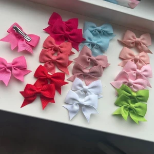 Färgglada hårrosetter i olika nyanser - Säljer ett set med hårrosetter i flera färger som röd, rosa, blå, vit, grön och beige. Rosetterna är gjorda i ribbat tyg och har metallclips på baksidan för enkel fastsättning i håret. Perfekt för att piffa till frisyren med en söt detalj.