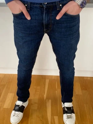 Mörkblå skinny jeans från tiger of Sweden  - Säljer ett par mörkblå skinny jeans från Tiger of Sweden med klassisk femficksmodell och läderpatch bak i midjan. Jeansen har smal passform och är tillverkade i stretchigt denimtyg för extra komfort. Perfekta för en trendig och avslappnad look.