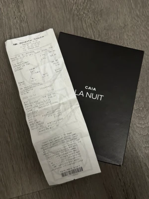 CAIA La Nuit parfym - Säljer en CAIA La Nuit parfym i en stilren svart kartong med vit text. Märket CAIA är känt för sina trendiga och exklusiva dofter. Förpackningen ger en lyxig känsla och passar dig som gillar snygg design och moderna parfymer.