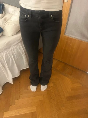 Svarta bootcut jeans med stretch - Säljer ett par svarta bootcut jeans med klassisk femficksmodell och stretchigt material. Jeansen har normal midja och subtila slitningar för en avslappnad look.