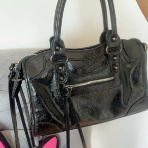 Läderimitation väska  - Cool väska i glansigt läderimitation och snygga nit detaljer (väskan är i jätte bra skick inga fläckar de är ljuset som reflekterar på bilden) 