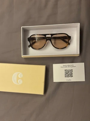 Bruna solglasögon från Corlin - Snygga solglasögon från Corlin med brunmelerad båge och bruna glas. Klassisk rektangulär form som passar till de flesta stilar. Kommer i originalförpackning med tillhörande fodral. Använda 3-4 gånger! Kostar ca 1400 nya!