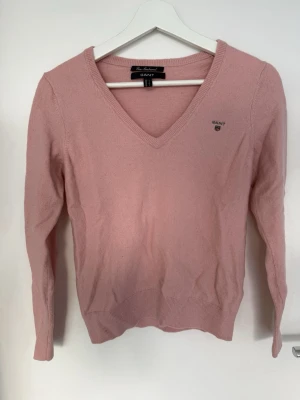 Stickad tröja från Gant - Fin stickad tröja i 100% lambswool med v-ringning. Är egentligen i strl L men feltvättad så är därav som en xs. Använd och något nopprig men annars i fint skick. En liten fläck på armen (se sista bilden) som jag inte försökt tvätta bort så osäker på om det går att åtgärda.