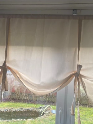 JOTEX Beige hissgardin med band - Elegant hissgardin från Jotex, modell Versailles Rand. Tillverkad i 100% polyester med ett stilrent randigt mönster. Perfekt för att skapa en mjuk och behaglig atmosfär i rummet. 2 stycken - 140x90 cm, beige. Färdiga att hänga. I nyskick. Använda i några månader bara.  