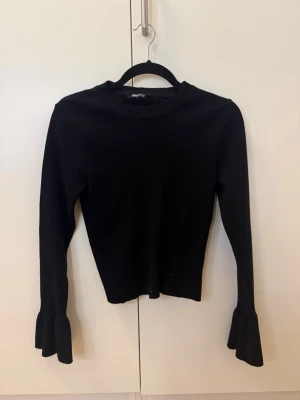 Svart stickad tröja med trumpetärm - Hejhej!🥰 Säljer en trendig svart stickad tröja med långa trumpetärmar och rund hals. Ribbstickad struktur som ger en snygg passform. Perfekt att matcha med jeans eller kjol för en cool look. I ryggen har den en vacker design som passar till varje outfit! Skriv om det är något ni undrar!🌸