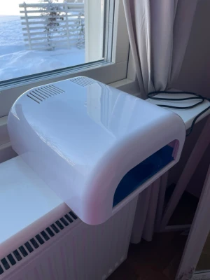 Vit UV-lampa för naglar - UV-lampa för naglar och för att enkelt härda gelélack eller nagelförlängningar. Drivs med sladd och passar perfekt för hemmabruk. Dock glappar lamporna när man väl har satt i kontakten men annars lyser de precis som vanligt. Den fungerar utmärkt!