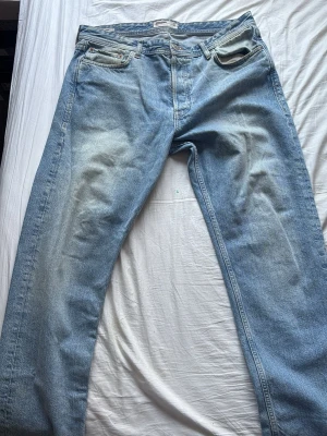 Ljusblå loose fit jeans Jack & Jones - Säljer ett par ljusblå loose fit jeans från Jack & Jones. Jeansen har klassisk femficksdesign, raka ben och slitningar för en avslappnad look. Materialet är denim i bomull och passformen är rymlig och bekväm. Perfekta för en casual stil.