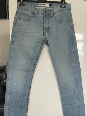 Ljusblå skinny jeans från Topman - Säljer ett par ljusblå skinny jeans från Topman, modell Moto. Jeansen har klassisk femficksdesign, normal midja och smal passform hela vägen ner. Perfekta för dig som gillar en clean och enkel look. Tillverkade i denim med lite stretch. Midjemått 76 cm , Innerbenslängd 74 cm 