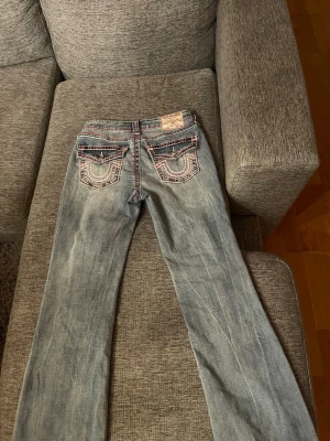 True Religion ljusblå bootcut jeans - Säljer ett par ljusblå jeans från True Religion med bootcut modell. Byxornas passform är mid waist. Byxorna är aldrig använda förutom på bilden och har inga hål eller fläckar. Säljes pågrund av att dem tyvärr inte kom till användning. Orginal pris: 2300kr. Prislappen är inte kvar, och inte orginal påsen heller men som sagt är byxorna i jätte bra skick. Skriv om du undrar något! 