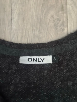 Lång svart kofta från ONLY - Säljer en lång, svart kofta från ONLY i storlek S. Koftan har öppen front, långa ärmar och är gjord i ett mjukt, stickat material. Perfekt att slänga över en outfit för extra värme och stil.