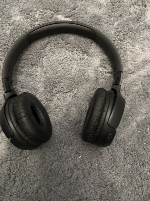 Svarta over-ear hörlurar från jbl - Snygga svarta over-ear hörlurar med vadderad bygel och mjuka öronkuddar i konstläder. Perfekta för musik, gaming eller videos. Trådlös design med knappar på sidan för enkel styrning.