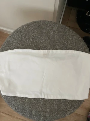 Vit bandeau tubtopp från Divided - Säljer en enkel och stilren vit bandeau tubtopp från Divided. Toppen är axelbandslös och har en rak passform, perfekt att matcha med höga jeans eller kjol. Materialet är mjukt och bekvämt, vilket gör den superenkel att bära till olika outfits.