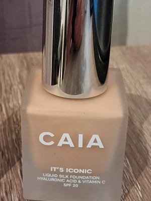 CAIA It's Iconic Foundation SPF 20 - Flytande foundation från CAIA, It's Iconic, i nyansen 3N (brige). Kommer i en fyrkantig glasflaska med silverfärgad pump. Innehåller hyaluronsyra och vitamin C samt har SPF 20. Ger en naturlig, silkeslen finish och är lätt att applicera.
