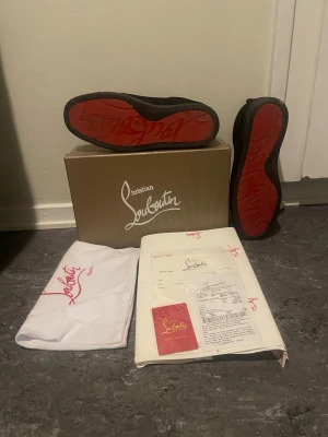 Christian Louboutin svarta sneakers - Säljer ett par svarta sneakers från Christian Louboutin med den ikoniska röda sulan. Skorna har en klassisk låg siluett och är tillverkade i läder. Kommer med originalkartong, dustbag och äkthetsbevis. Perfekta för dig som vill sticka ut med exklusiva detaljer. Passar 42-43 pris kan diskuteras