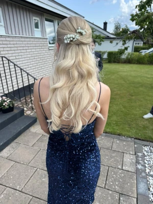 Marinblå glittrig långklänning - Säljer en marinblå långklänning med tunna axelband och v-ringning. Klänningen är täckt av glittriga paljetter, har snörning i ryggen och en hög slits framtill. Perfekt för bal eller festliga tillfällen.