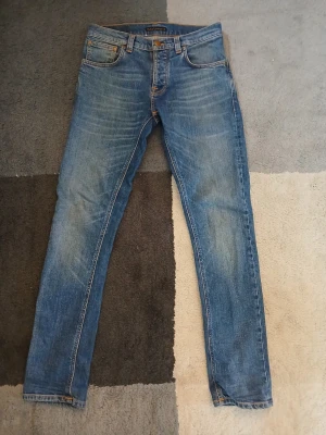 Blå Nudie Jeans - Säljer ett par klassiska blå jeans från Nudie jeans. Modellen är grim tim och måtten är 106cm i längden och 40 cm i midjan. Säljer endast för att dom inte längre passar