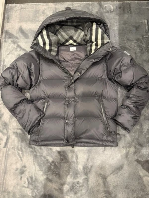 Burberry Pufferjacka, svart - Tjena! Säljer nu denna berburry jackan. Nyskick använd 1 eller 2 gånger. Storlek S, sitter lite större i storlek. Medföljer nerburet taggarna. Vid frågor kontakta gärna! Har en liten repa på baksidan därav priset 