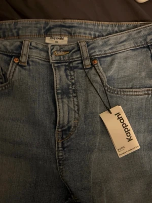 Ljusblå raka jeans från Kappahl - Snygga ljusblå jeans från Kappahl med raka ben och klassisk femficksmodell. Jeansen har bälteshällor, knappgylf och är tillverkade i ett slitstarkt denimtyg. Perfekta för en avslappnad och trendig look. Aldrig använda! Med prislapp kvar.