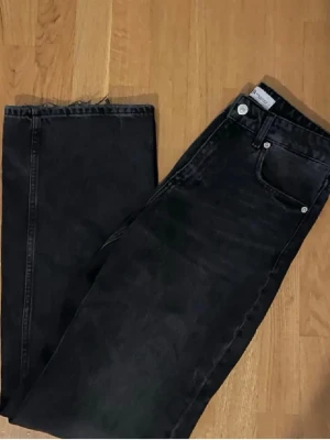 Svarta straight jeans från Zara - Snygga svarta/mörkgrå jeans från Zara med klassisk femficksdesign och raka ben. Jeansen har medelhög midja och är tillverkade i ett mjukt bomullsmaterial med en lätt tvättad look. Perfekta för dig som gillar en clean och enkel stil.