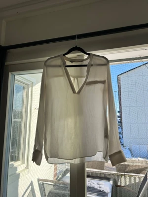 Vit blus med v-ringning - Stilren vit blus med djup v-ringning och långa ärmar. Använd få gånger