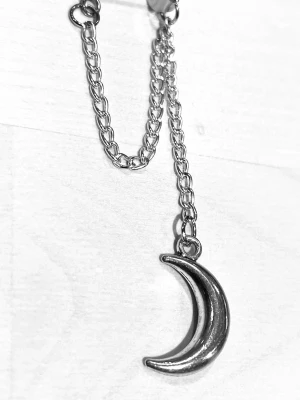 By prisförslag- 1 st Silvrigt örhänge med månhänge - Snyggt örhänge i silverfärgad metall med en kedja och ett hängande månhänge. Örhänget har en cool och unik design som sticker ut och passar perfekt för dig som gillar detaljer med lite edge. Ingen pärla, bara metall och kedja.