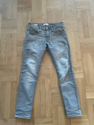 Grå Jeans J&J - Gråa jeans av märket Jack & Jones, väldigt bra skick. Storlek W29 L30 och har inga defekter. Hör av dig vid frågor eller funderingar! * Fraktas samma dag som köp (gäller vid köp innan kl 18.00).