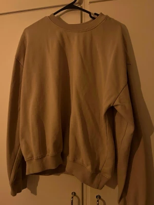 Beige oversized sweatshirt - En enkel beige sweatshirt i oversized modell med rund halsringning och ribbade muddar vid ärmslut och nederkant. Tröjan är tillverkad i mjukt bomullsmaterial och har en avslappnad passform som passar perfekt till jeans eller mjukisbyxor.